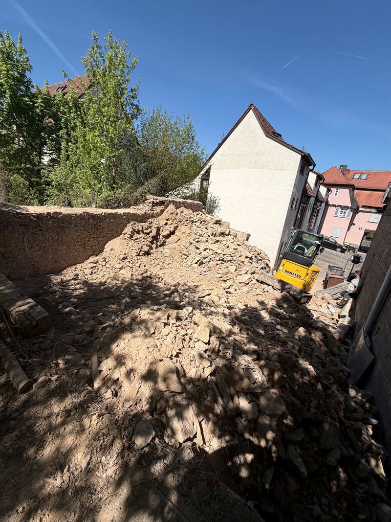 Minibagger beim Abbruch einer Bruchsteinmauer